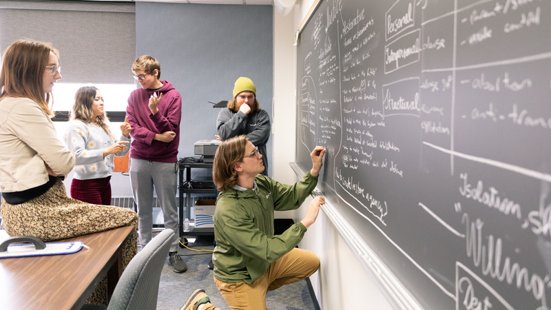 Gusties discussing over a chalk board.